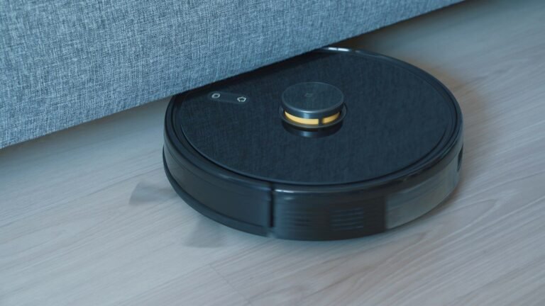 Black robot vacuum cleaner on a wooden floor, illustrating a robot vacuum buying comparison guide
